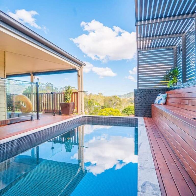 Elevated rectangular plunge pool with glass balustrade and timber decking overlooking scenic bushland views in Newcastle NSW