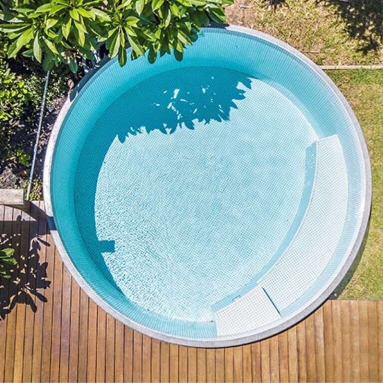 Aerial view of a circular plunge pool with light blue tiles surrounded by timber decking and greenery in Newcastle NSW