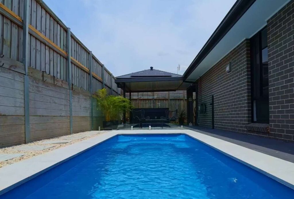 Newly installed fibreglass pool installation in Bateau Bay with modern paving and frameless glass fencing.
