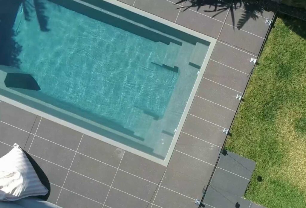 Angled aerial shot of a rectangular fibreglass plunge pool with integrated entry steps and contemporary paving