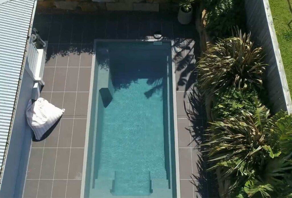 Overhead view of a modern plunge pool installation surrounded by tropical landscaping and spacious tiled pool surrounds