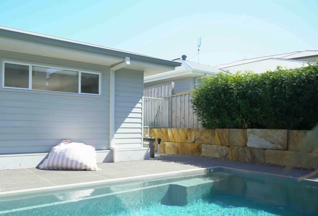 Contemporary backyard fibreglass pool with clean paving lines, landscaped retaining walls, and compact outdoor layout in Gosford