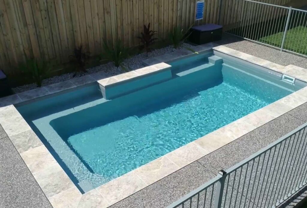Elevated angle of a custom fibreglass pool with integrated seating area and modern aluminium pool fencing